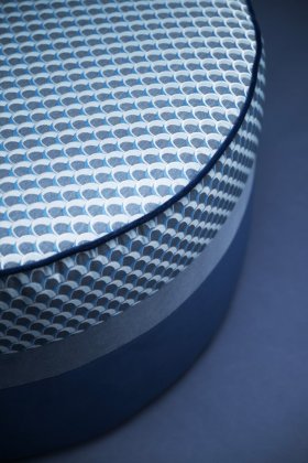 Dettaglio di un pouf cilindrico con tessuto ad archi.