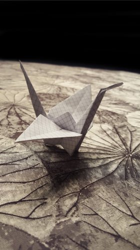 Un cigno origami su un tessuto con disegno di foglie di loto
